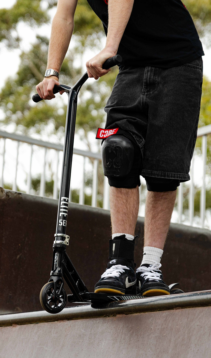 Rider standing with the Grit Elite 5er stunt scooter at a skatepark